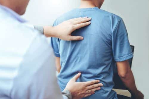 Doctor treating man in blue shirt with chiropractic care. 